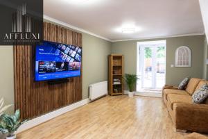a living room with a couch and a flat screen tv at Relaxing Ironbridge Hot Tub Retreat in Ironbridge