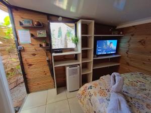 Una pequeña habitación con una cama y un televisor. en Les cabanes éco-responsables, en Saint-Louis