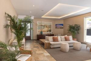 a living room with a white couch and palm trees at Hotel Baltum in Albufeira