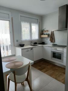 Una cocina con gabinetes blancos y una mesa con sillas. en Casa Bedoll, en Miami Platja