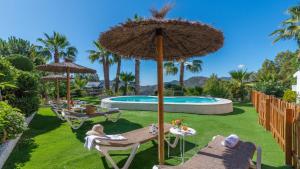 patio z parasolem i krzesłami oraz basenem w obiekcie Villa Gran Solano Colmenar by Ruralidays w mieście Colmenar