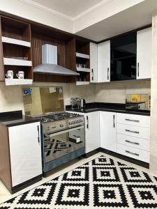 a kitchen with white cabinets and a stove top oven at Royal Suite near City Star Mall 3 Bedroom Apart in Cairo