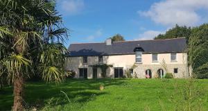 a large white house with a palm tree in front of it at Auberge de la Hardouinais-Arduen in Saint-Launeuc