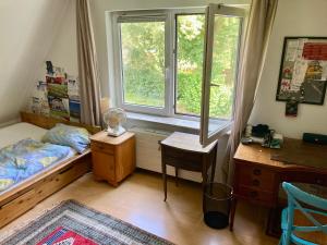 a bedroom with a bed and a desk and a window at Privatzimmer am Volkspark - Nähe Arenen und Trabrennbahn in Hamburg