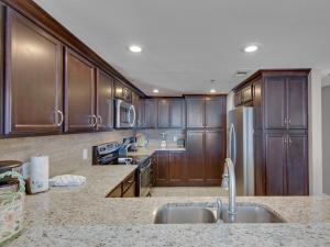a kitchen with wooden cabinets and stainless steel appliances at Jade East Towers 1050 by Newman-Dailey in Destin +17 photos