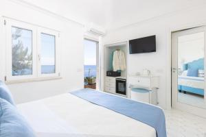 a white bedroom with a bed and a tv at Villa Nannina in Positano