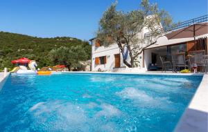 una piscina con agua azul frente a una casa en Gorgeous Home In Ploce, en Ploče