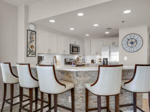 una cocina con armarios blancos y un bar con taburetes en Jade East Towers 1450 by Newman-Dailey, en Destin