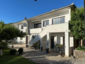 ein großes weißes Haus mit einem Baum davor in der Unterkunft Villa Beba - Apartments in Senj
