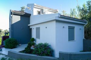 a white house with some plants in front of it at Appartement pour deux personnes in Patitiri