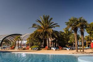 a resort with palm trees and a swimming pool at Mer et Soleil 5 étoiles à Oléron empl 170 3CH 1SDB 8 personnes in Les Sables Vignier