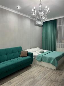 a bedroom with a bed and a couch and a chandelier at Sairam-16 уютная квартира Nurly zhol in Promyshlennyy