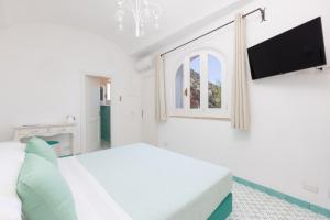 a white bedroom with a bed and a flat screen tv at Villa Nannina in Positano