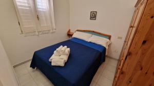 een slaapkamer met een blauw bed met handdoeken erop bij Case Centro Lampedusa in Lampedusa
