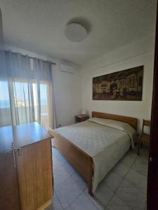 a bedroom with a bed and a desk and a window at Casa Yuliya in Letojanni