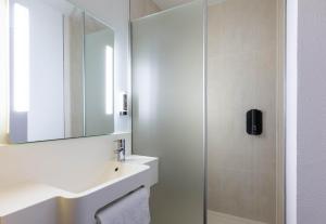 a white bathroom with a sink and a mirror at B&B HOTEL Lille Roubaix Campus Gare in Roubaix