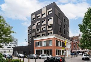 a tall black building with cars parked in a parking lot at B&B HOTEL Lille Roubaix Campus Gare in Roubaix