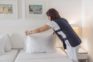 a woman is putting a pillow on a bed at Hotel Baltum in Albufeira
