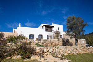 a white house on top of a stone wall at Hotel Rural Can Pujolet in Santa Agnès de Corona