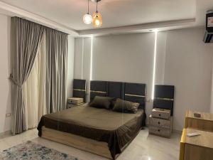 ein Schlafzimmer mit einem Bett und zwei Nachttischen in der Unterkunft شقة فندقية غرفتين بكمبوند قرب ميدان جهينة in Sheikh Zayed