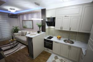 a kitchen with white cabinets and a couch in a room at Imperial Lux Apartment in Kragujevac