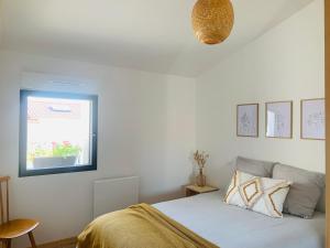 a white bedroom with a bed and a window at Le Solier, gîte à la campagne in Frossay