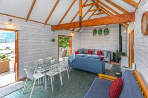 a living room with a couch and a table and chairs at The Beach House - Tairua Holiday Home in Tairua