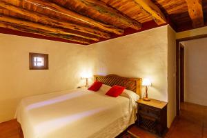a bedroom with a white bed with two red pillows at Hotel Rural Can Pujolet in Santa Agnès de Corona