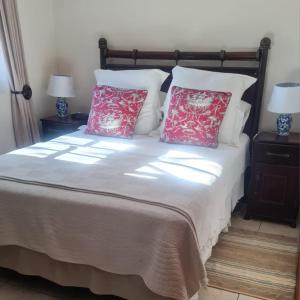 a bed with two red pillows and two lamps at Castelo Sutil Guest House in Bloemfontein