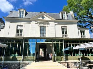 a large white house with a revolving door at Il Maestro - hôtel Restaurant du Château in Écouen