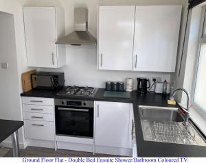 una cucina con armadi bianchi, piano cottura e lavandino di The Prince Albert, Whitton a Whitton Altre 11 foto