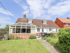 a white house with a conservatory in a yard at Daisy Cottage in Lincoln