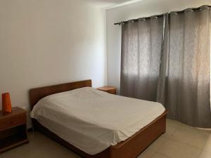 a small bedroom with a bed and a window at Vannimar t2 in Porto Novo