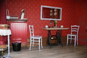 Habitación con mesa, sillas y pared roja. en Studios Jps en Les Flaches