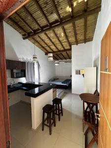 Una cocina con una encimera negra y algunos taburetes. en Recanto Mucugê, en Porto Seguro