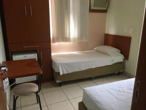 a bedroom with two beds and a table and a chair at Novo Grande Hotel in Ribeirão Preto
