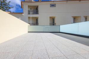 ein großes weißes Gebäude mit einer Glaswand in der Unterkunft Casa do Beco do Barlavento in Vila Baleira