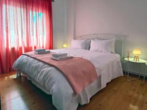 a bedroom with a large white bed with red curtains at Meli City Lodge in Volos
