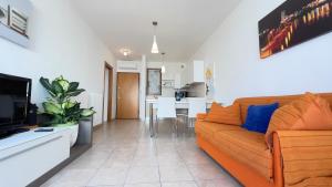a living room with a couch and a kitchen at Mazzarona Family Apartment - Luminoso appartamento con piscina al secondo piano in Sirmione