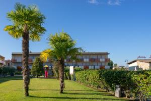 two palm trees in front of a building at Mazzarona Family Apartment - Luminoso appartamento con piscina al secondo piano in Sirmione