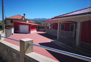 ein Gehweg, der zu einem roten Haus mit einer Garage führt in der Unterkunft Casa Valente in Ponte da Barca