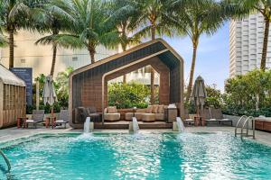 a pool with a couch and chairs and palm trees at EAST Miami in Miami