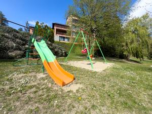Um parque infantil vazio com um escorregador laranja e verde. em El Refugio de Enveitg em Enveitg mais 13 fotografias