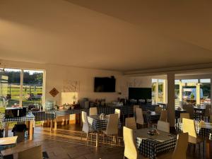 a restaurant with tables and chairs and a television at Chill Out Wygryny in Ruciane-Nida