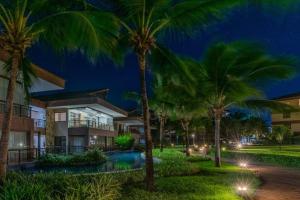 a villa with palm trees at night at Mandara Lanai Apartamento Bangalô in Aquiraz