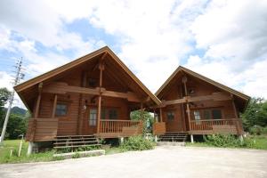 a log cabin with two decks on a field at Log Cottage Tomato in Hakuba