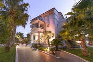 a white house with palm trees in front of it at Tresor Sousouras in Hanioti