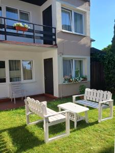 two white chairs and a table in front of a house at Pokoje Gościnne Jana in Łeba