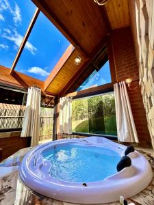 a hot tub in a room with a large window at Pousada Verdes Alpes in Santo Antônio do Pinhal