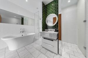 a bathroom with a tub and a sink and a mirror at Central London Spectacular riverview two bedroom Luxury designer apartment-AC-Parking-WIFI-2 bathrooms in London